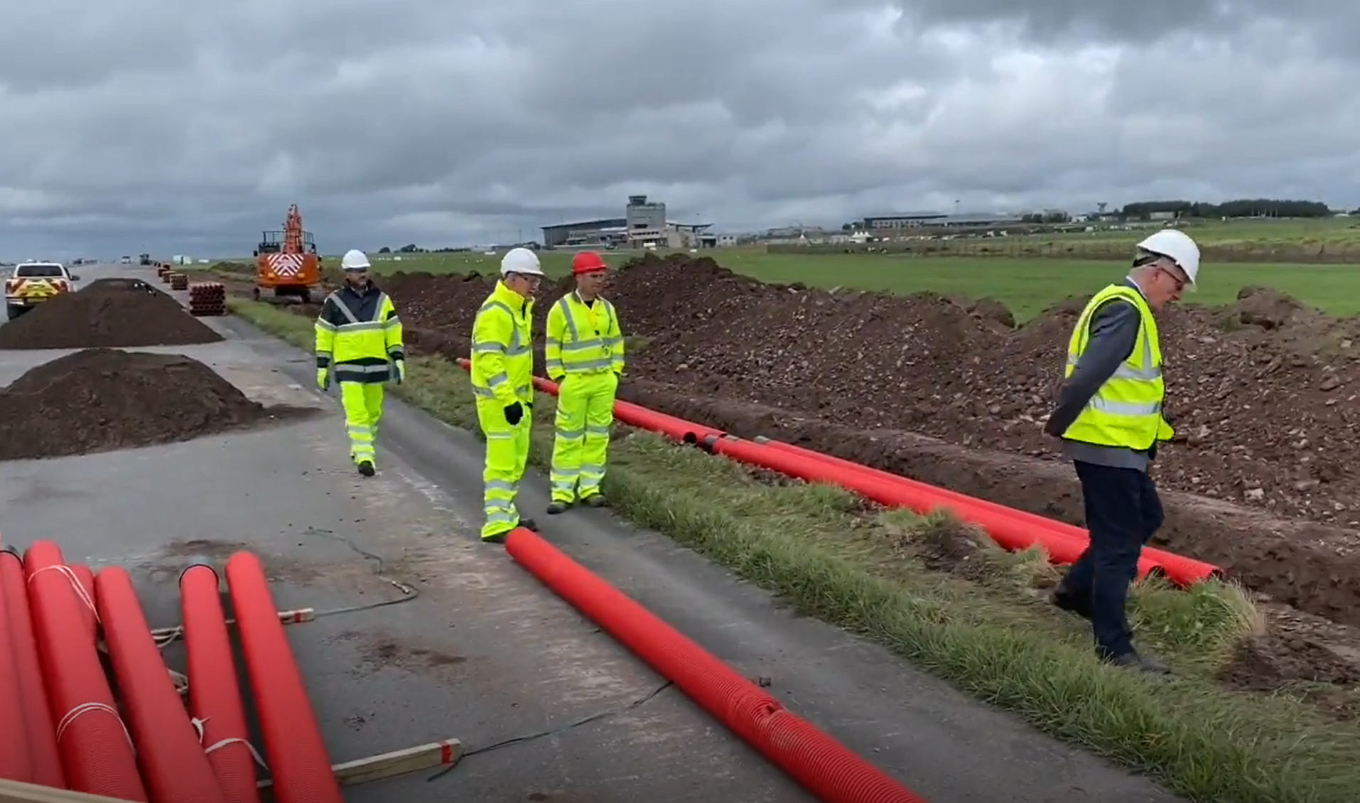 cork-airport-2 men looking over a ditch at pipes being installed in a man made ditch at cork airport